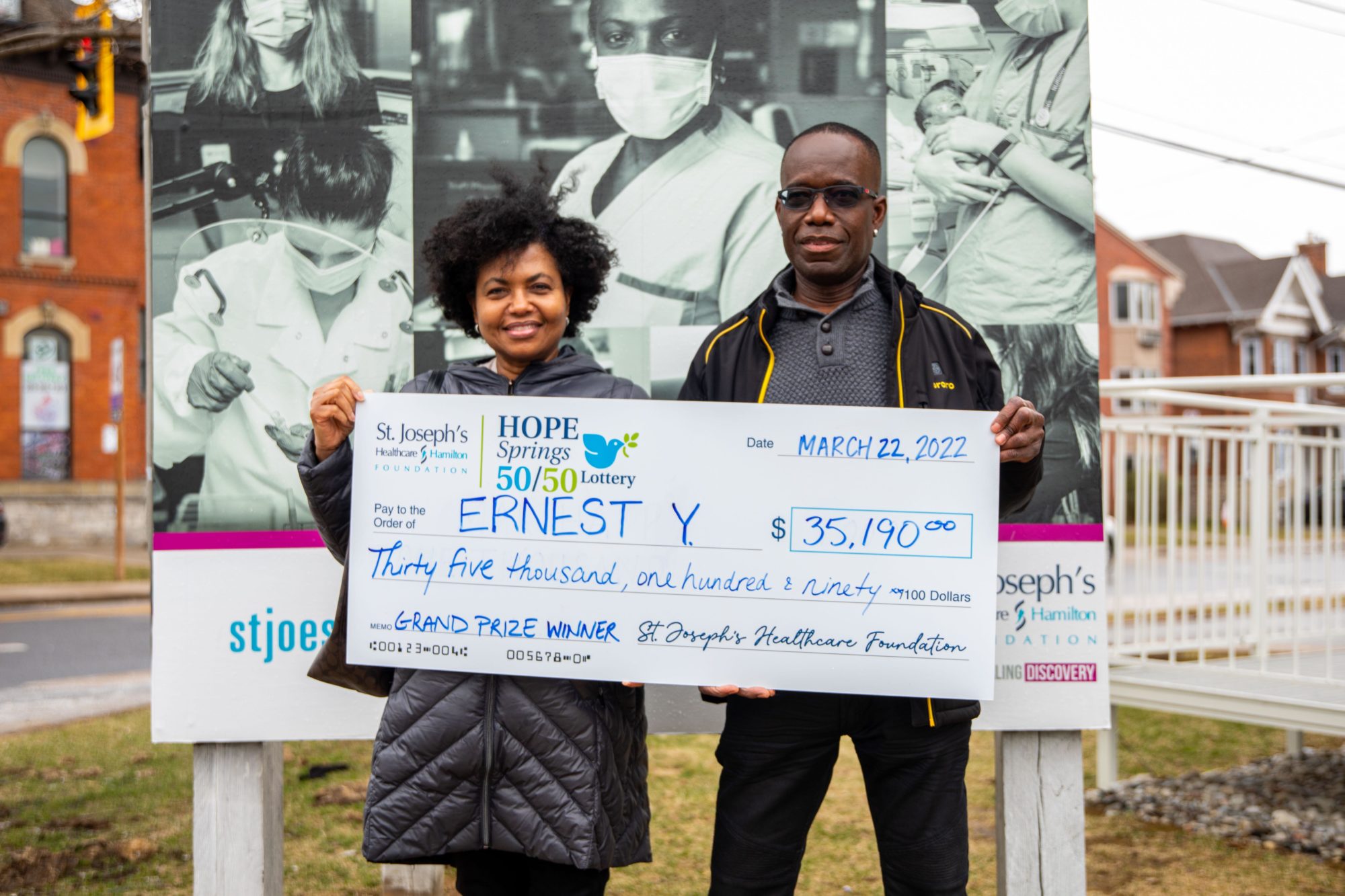A photo of our grand prize lottery winner. The couple smiles while holding up a large novelty cheque for $35,190.